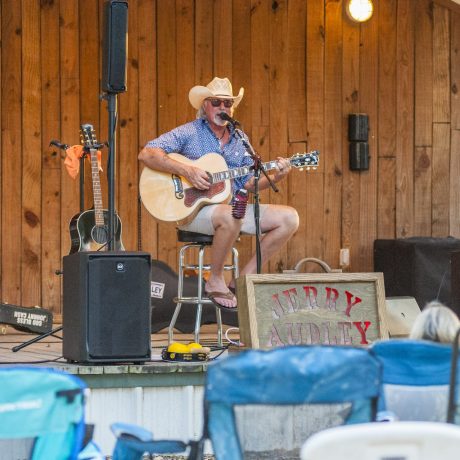 man playing guitar outdoor on a stage at Great Escapes RV Resorts Bryan College Station