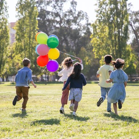 Children with balloons running in grass
