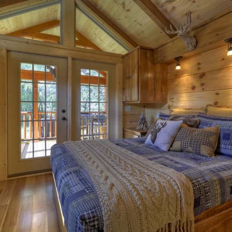Cabin interior with bed, doors, and trees outside