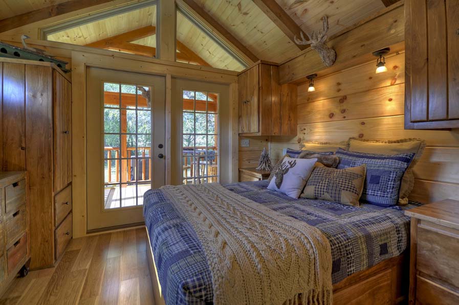 Cabin interior with bed, doors, and trees outside
