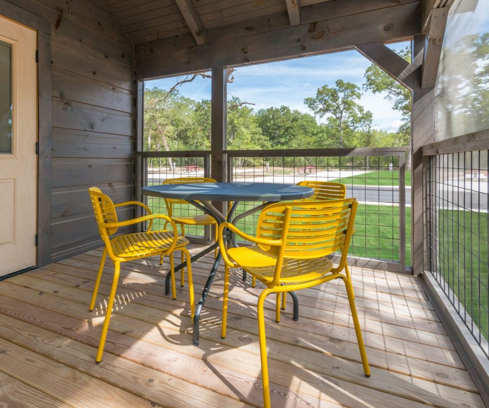 cabin rental porch with table at Great Escapes RV Resorts Bryan College Station
