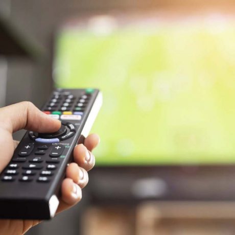 Hand holding remote control toward television