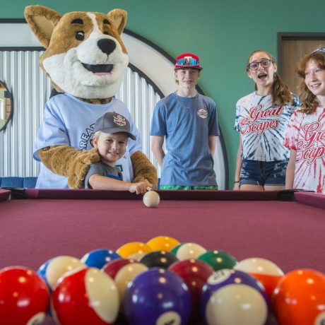 kids playing a game of pool with Biscuit the camp mascot at Great Escapes RV Resorts Bryan College Station