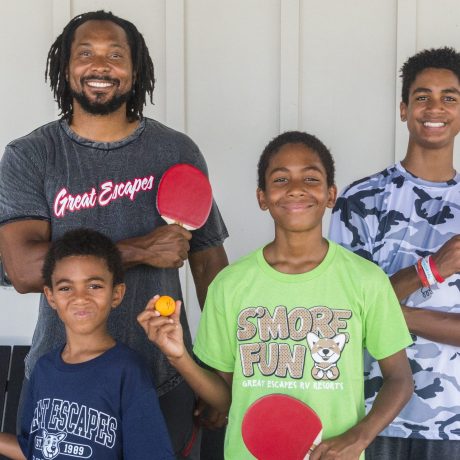 family holding ping pong paddleboards and smiling at Great Escapes RV Resorts Bryan College Station