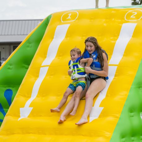girls sliding down Wibit water obstacle course at Great Escapes RV Resorts Bryan College Station