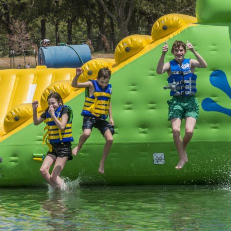 kids jumping off of Wibit water obstacle course at Great Escapes RV Resorts Bryan College Station