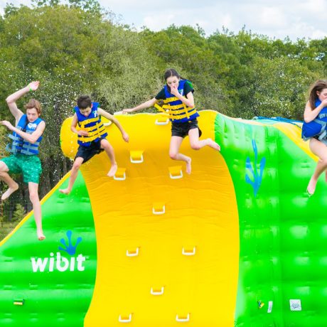 kids jumping off of Wibit water obstacle course at Great Escapes RV Resorts Bryan College Station